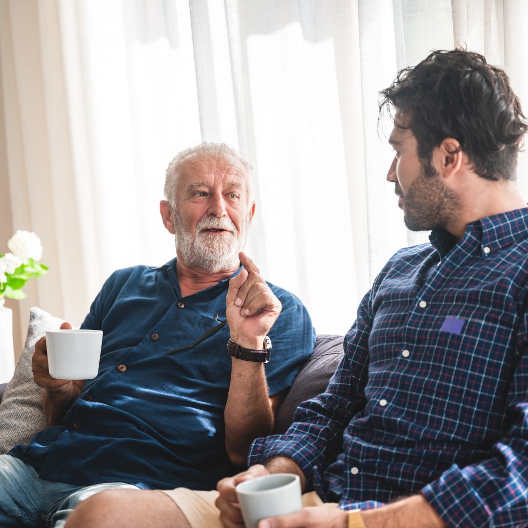 Elderly Father and son talking with cup of coffee in hand
